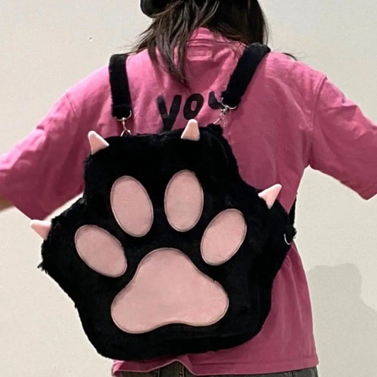 Cute black and pink cat paw plush backpack with adjustable straps worn by a person in pink shirt, soft furry school bag for women and girls.